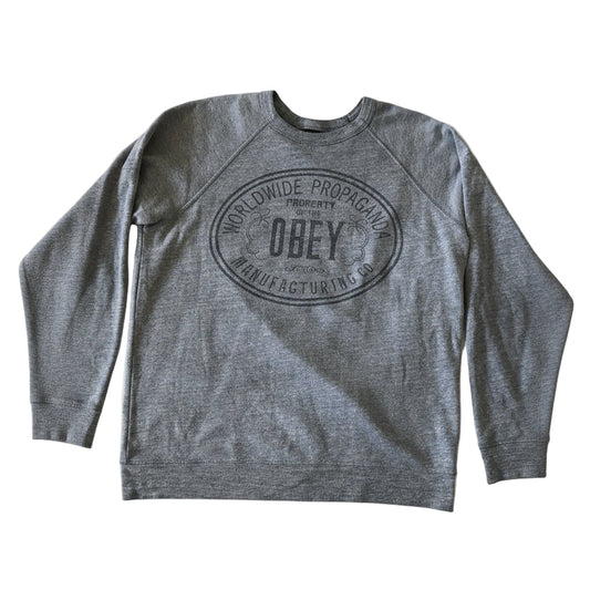 Gray sweatshirt with 'Obey' logo on a beige surface