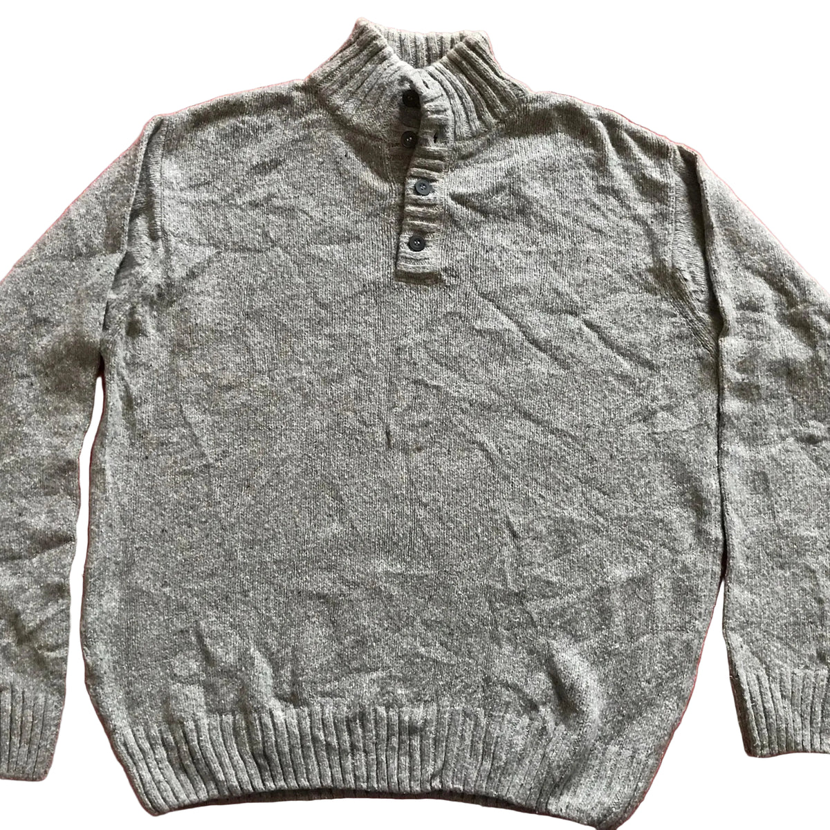 A gray heathered knit sweater with a mock neck and button placket, laid flat on a red fabric background.